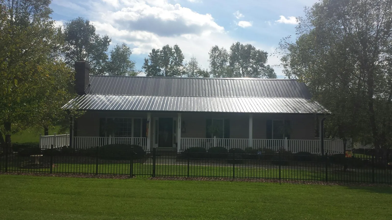Gray metal roof on a brick ranch with a full width front porch — Gutter Guard Installation work by our crew in Bethesda