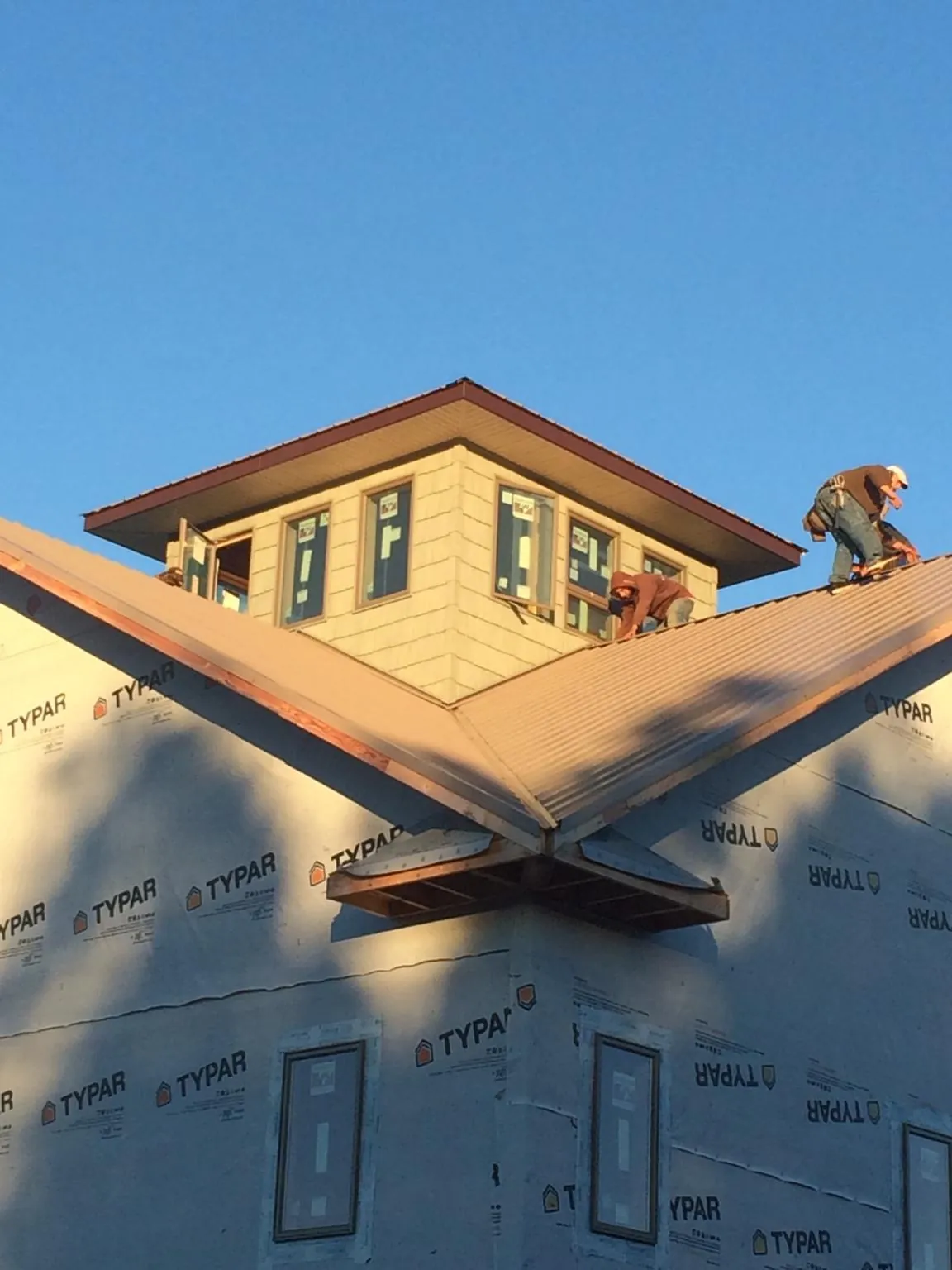 Roofers working around a rooftop cupola on a new metal roof at sunset — Roof Waterproofing in Bethesda by Roofing Brothers